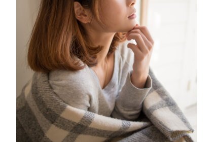 冷え性で体に毛布を羽織る女性