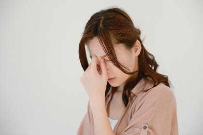 めまいに頭を押さえる女性