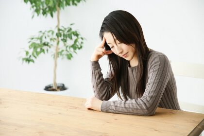 頭痛で頭を押さえる女性